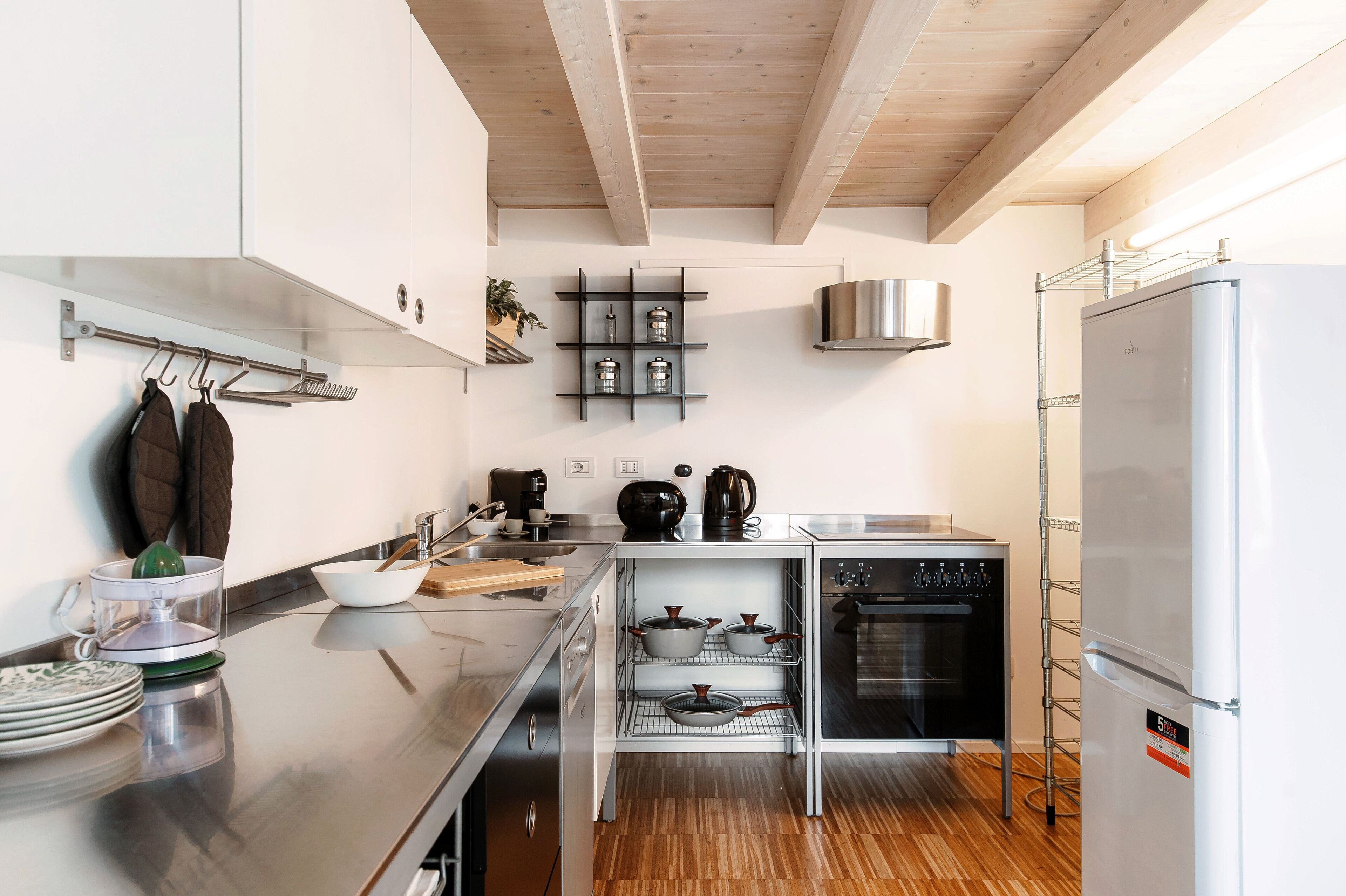 Una cocina moderna con electrodomésticos de acero inoxidable, vigas de madera y horno empotrado.