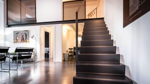 A modern interior with a black staircase, a seating area with a table, and a framed picture on the wall. - Porta Torre Lofts (Como)
