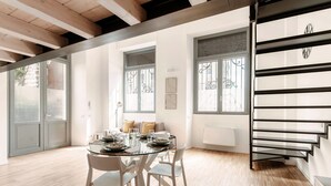 A dining area with a glass table, white chairs, and a staircase with a metal railing. - Porta Torre Lofts (Como)