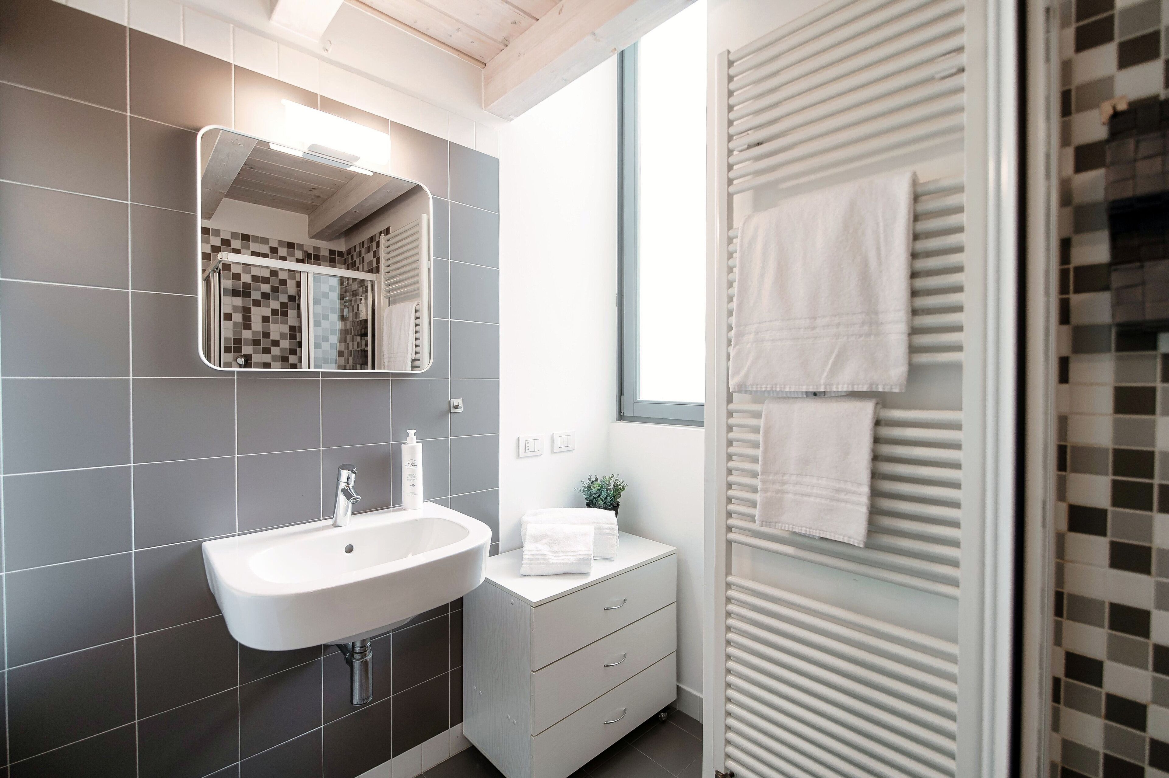 Een moderne badkamer met een witte wasbak, een spiegel en een handdoekhouder.