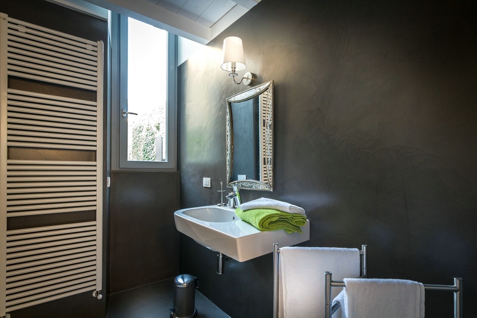 Un baño moderno con un ventanal grande, un lavamanos blanco, un espejo y un perchero para toallas.