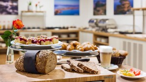 A breakfast buffet with bread, pastries, and a glass of milk on a wooden table. - Hotel Trezor (Singen)