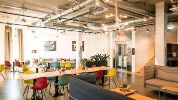 A modern office space with a long table, colorful chairs, and a sofa.