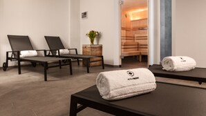 A spa room with two reclining chairs, a massage table, and a small plant. - Hotel Trezor (Singen)