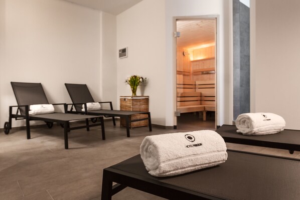 Un cuarto de spa con dos sillones reclinables, una camilla de masaje y una planta pequeña.