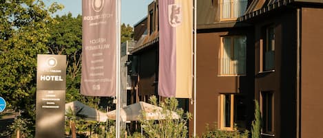 Un hôtel au design moderne, doté d’une enseigne bien visible et d’un espace extérieur bien entretenu, agrémenté de plantes et de parasols.