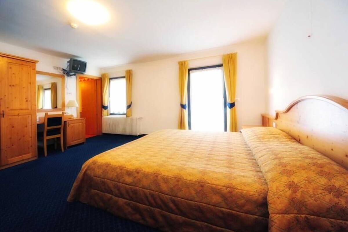 Una habitación de hotel con una cama grande, un escritorio y un armario.