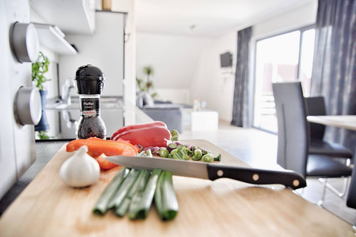 A kitchen with a cutting board, vegetables, and a knife.