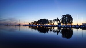 A marina at dusk with calm waters reflecting the boats and trees. - Haff-Ostseeferienhaus (Monkebude)