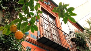 Um edifício com fachada vermelha, varanda com grades de metal ornamentadas e decoração com cabeça de leão.