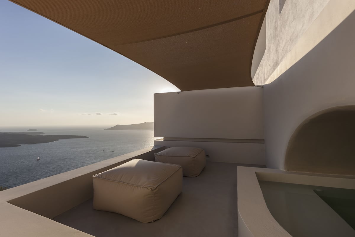 A modern balcony with a view of the sea, two beige cushions, and a minimalist design.