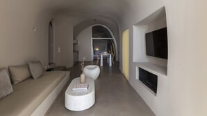 A modern living room with a sofa, a coffee table, and a TV mounted on the wall. - Aesthesis Villas Firostefani (Santorini)