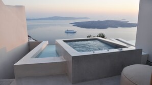 A modern outdoor hot tub with a view of a calm sea and distant islands. - Aesthesis Villas Firostefani (Santorini)