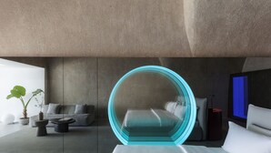 A modern bedroom with a circular bed, a sofa, and a coffee table. - Aesthesis Villas Firostefani (Santorini)