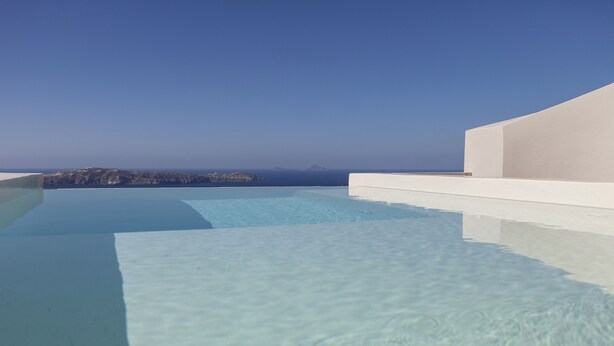 A clear blue sky and a pool with a view of a distant coastline. - Aesthesis Villas Firostefani (Santorini)