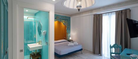 Une chambre d’hôtel avec un lit, une salle de bain avec un lavabo, une télévision et une fenêtre avec des rideaux.