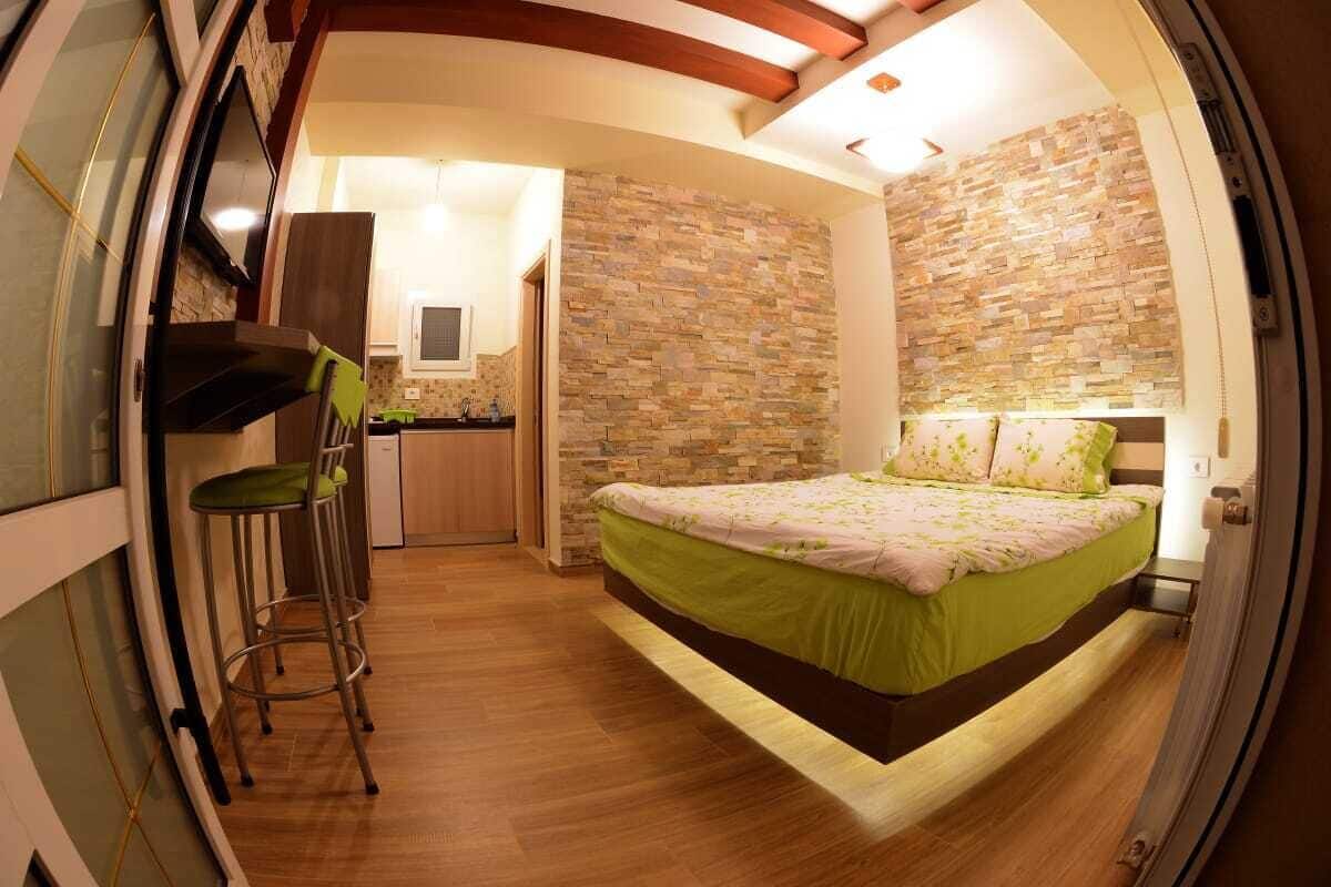 Une chambre compacte comprenant un lit, une petite kitchenette et une salle de bain.