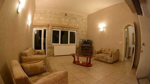 Una sala de estar con pared de piedra, un juego de sofá, una mesa de centro y un televisor.