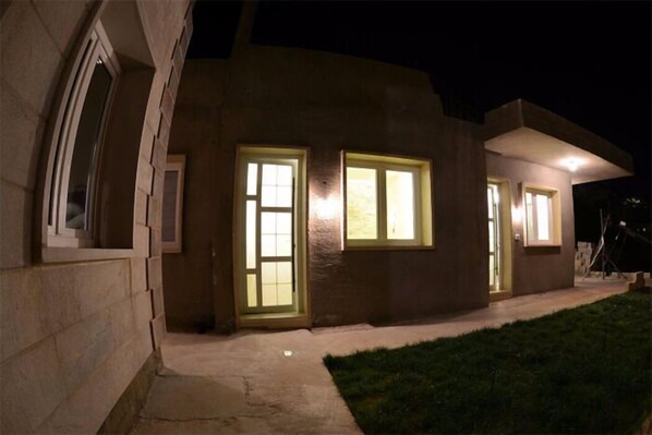 A modern house with three illuminated windows and a well-maintained lawn. - Bauhaus Chalets Apartment (Bcharré)