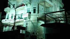 Un edificio de varios pisos con balcones y ventanas grandes, iluminado por la noche.