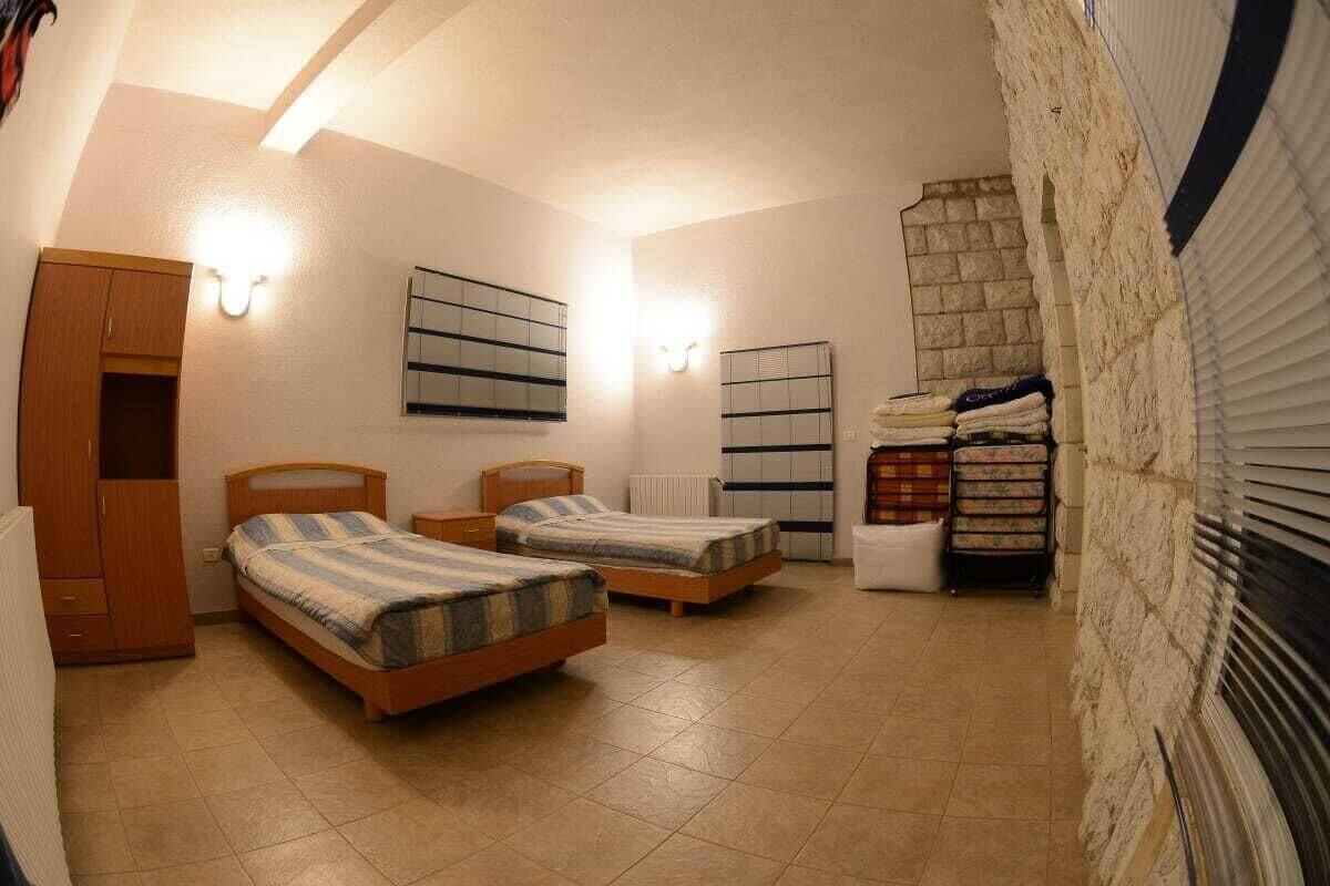 Une chambre avec deux lits simples, une armoire, un radiateur et un mur en pierre.