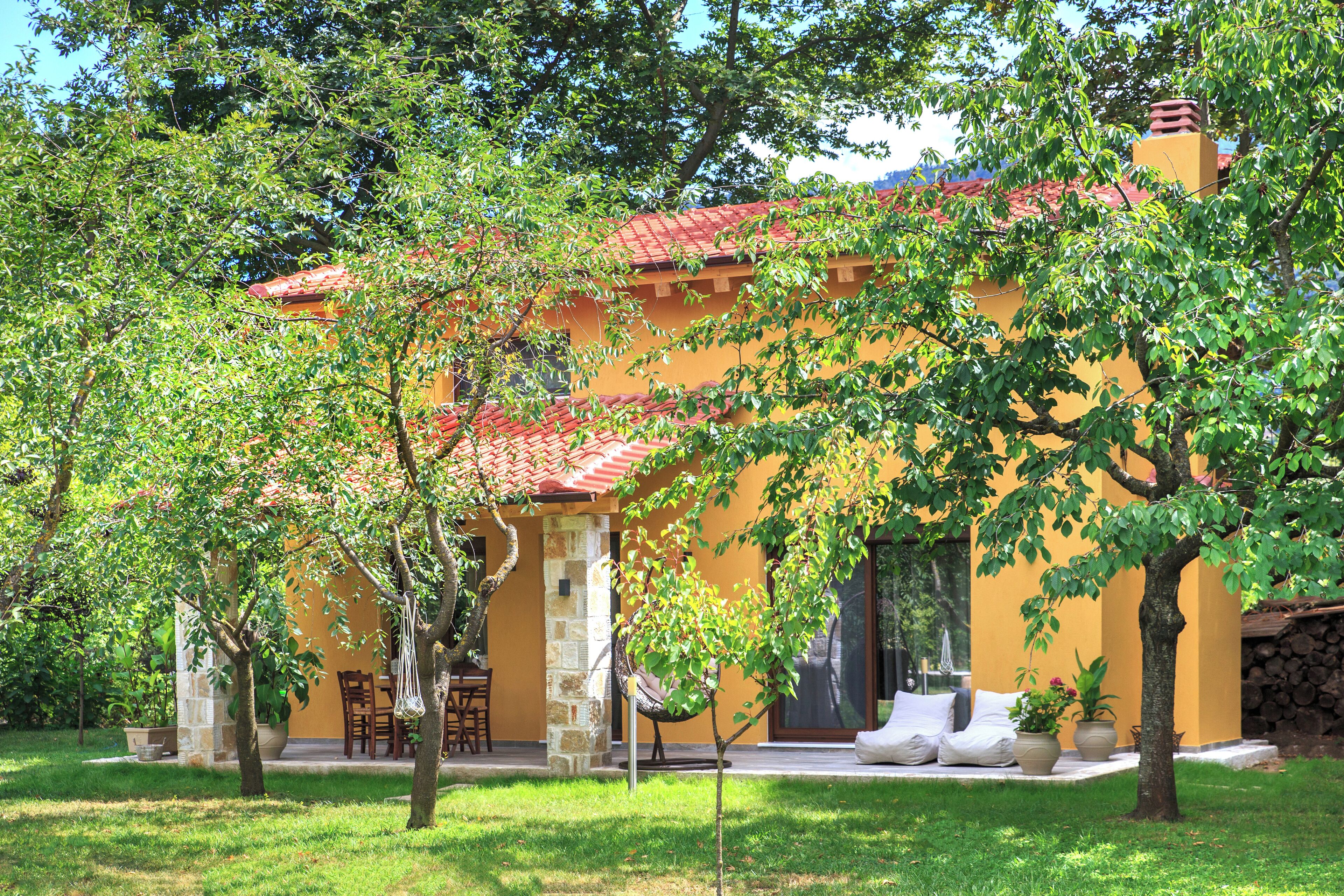 A yellow building with a red roof, surrounded by trees and a grassy lawn.