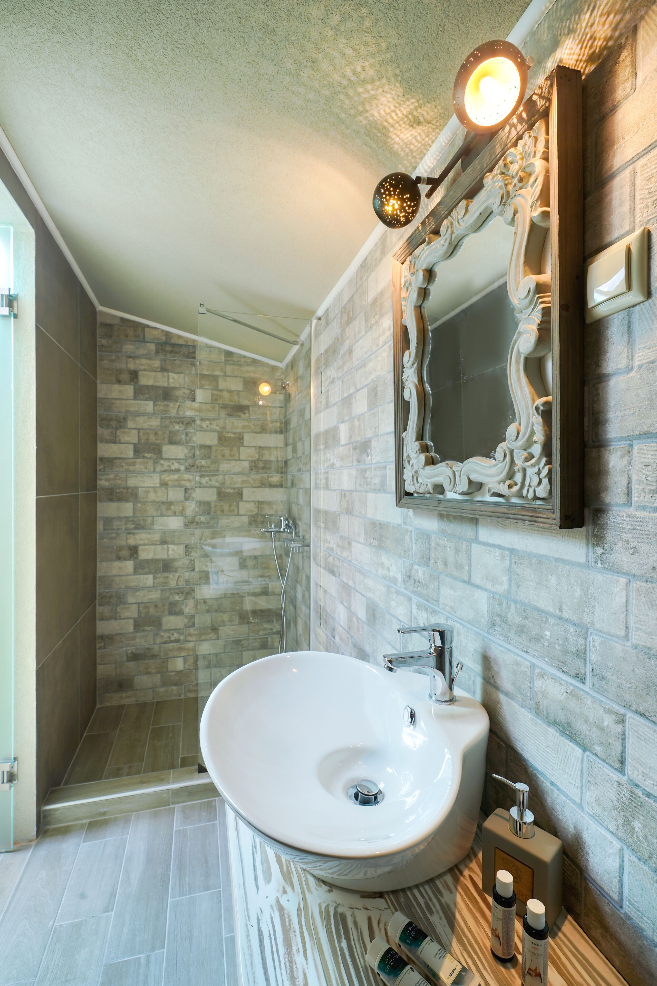 Un baño con un lavamanos blanco, un espejo y una ducha.
