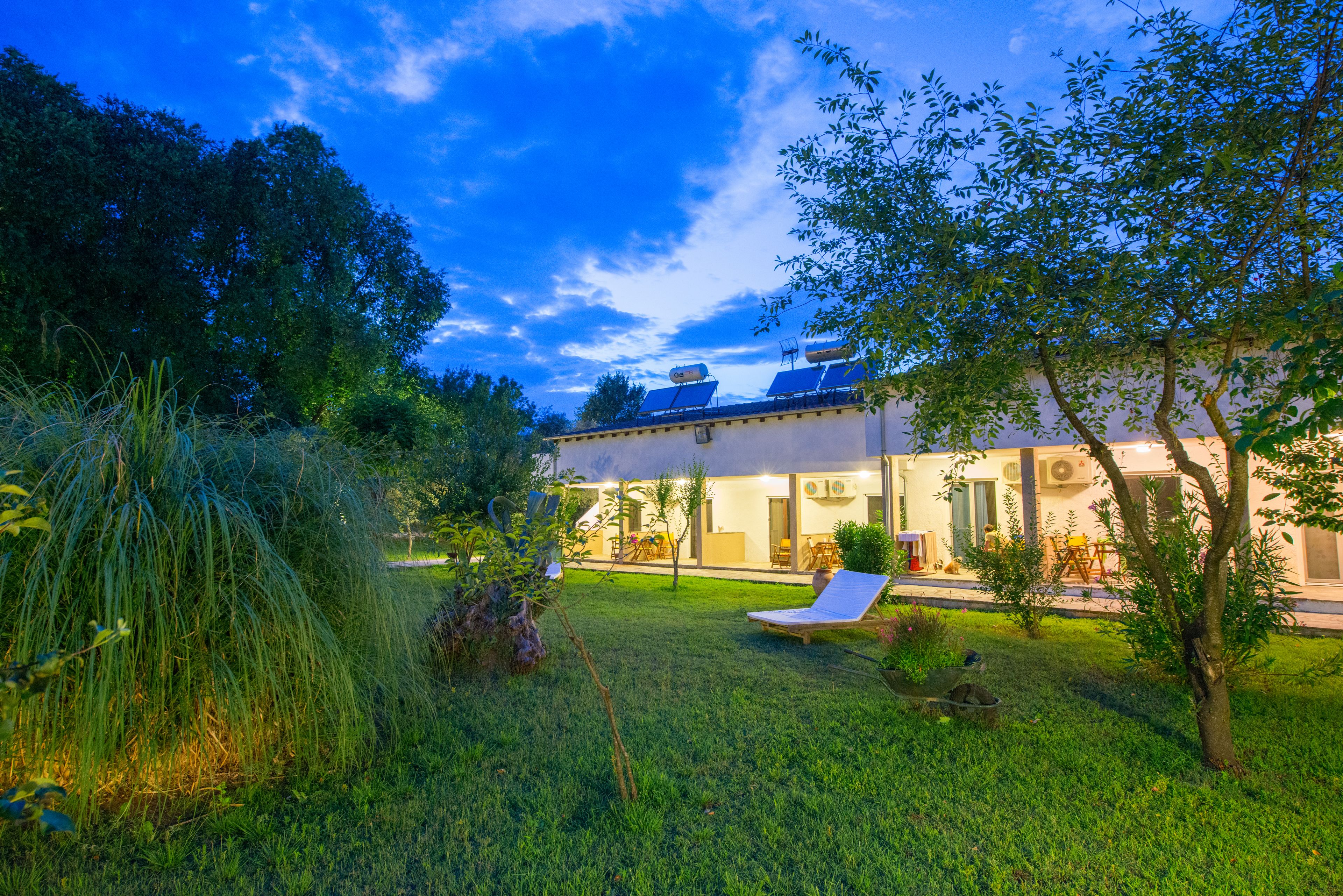 Una casa moderna con un jardín cuidado, una silla de descanso y paneles solares en el techo.