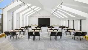 Une salle de classe moderne équipée de bureaux, de chaises, d’un écran de projection et de lucarnes.