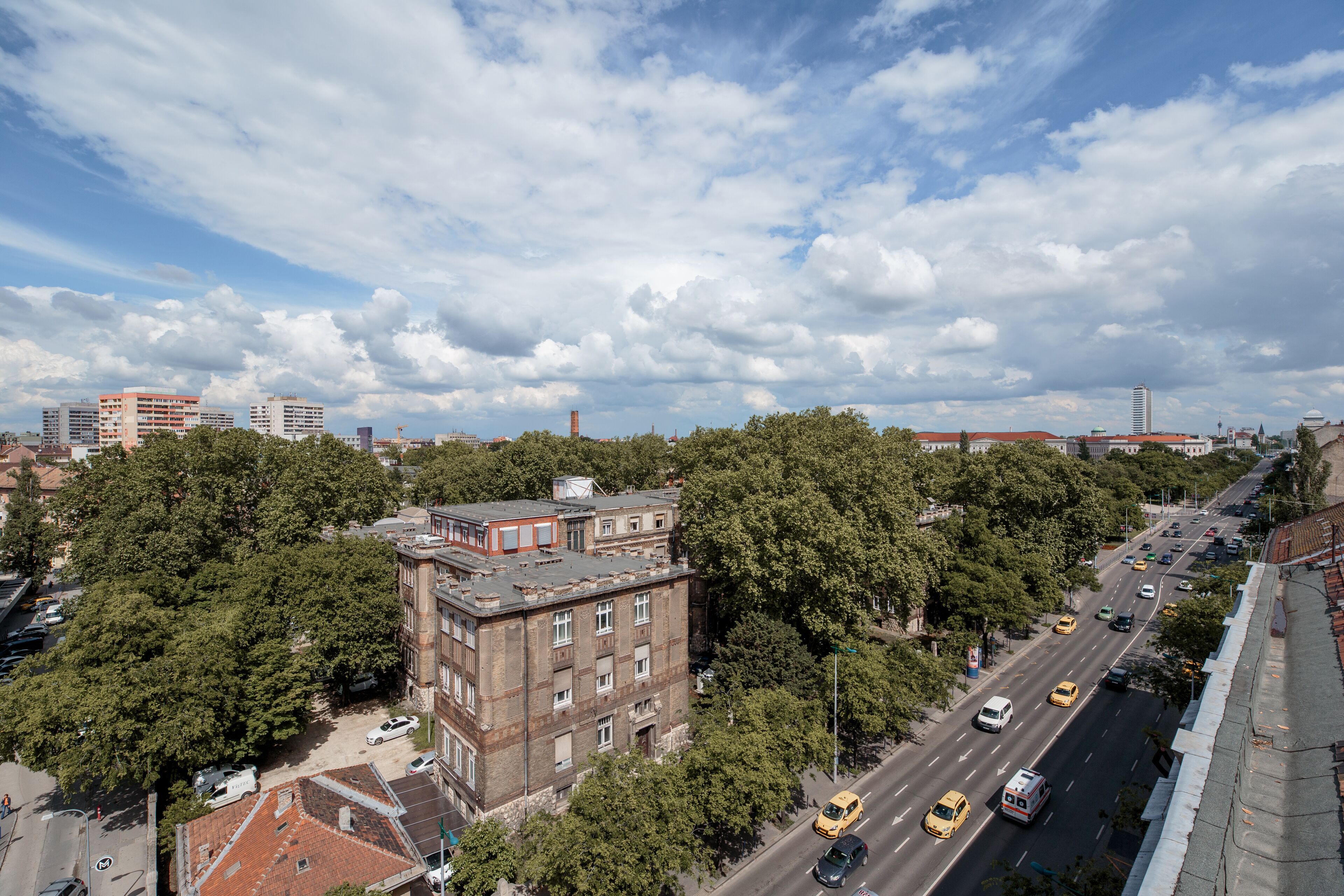 A cityscape with a prominent building surrounded by trees and a busy street with vehicles.
