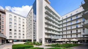 Un hôtel moderne à plusieurs étages, doté d’une cour intérieure, de sièges en plein air et de balcons.