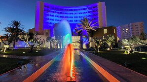 A hotel with a central fountain, palm trees, and a modern building with illuminated blue lighting. - Sousse Pearl Marriott Resort & Spa (Sousse)