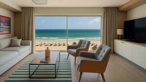 A modern hotel room with a large window offering a beach view, a sofa, two armchairs, a coffee table, and a flat-screen TV. - Sousse Pearl Marriott Resort & Spa (Sousse)