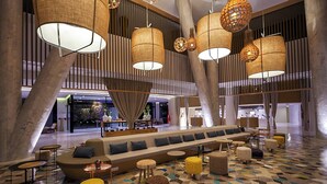 A spacious lobby with a long sofa, multiple seating areas, and hanging lamps. - Sousse Pearl Marriott Resort & Spa (Sousse)