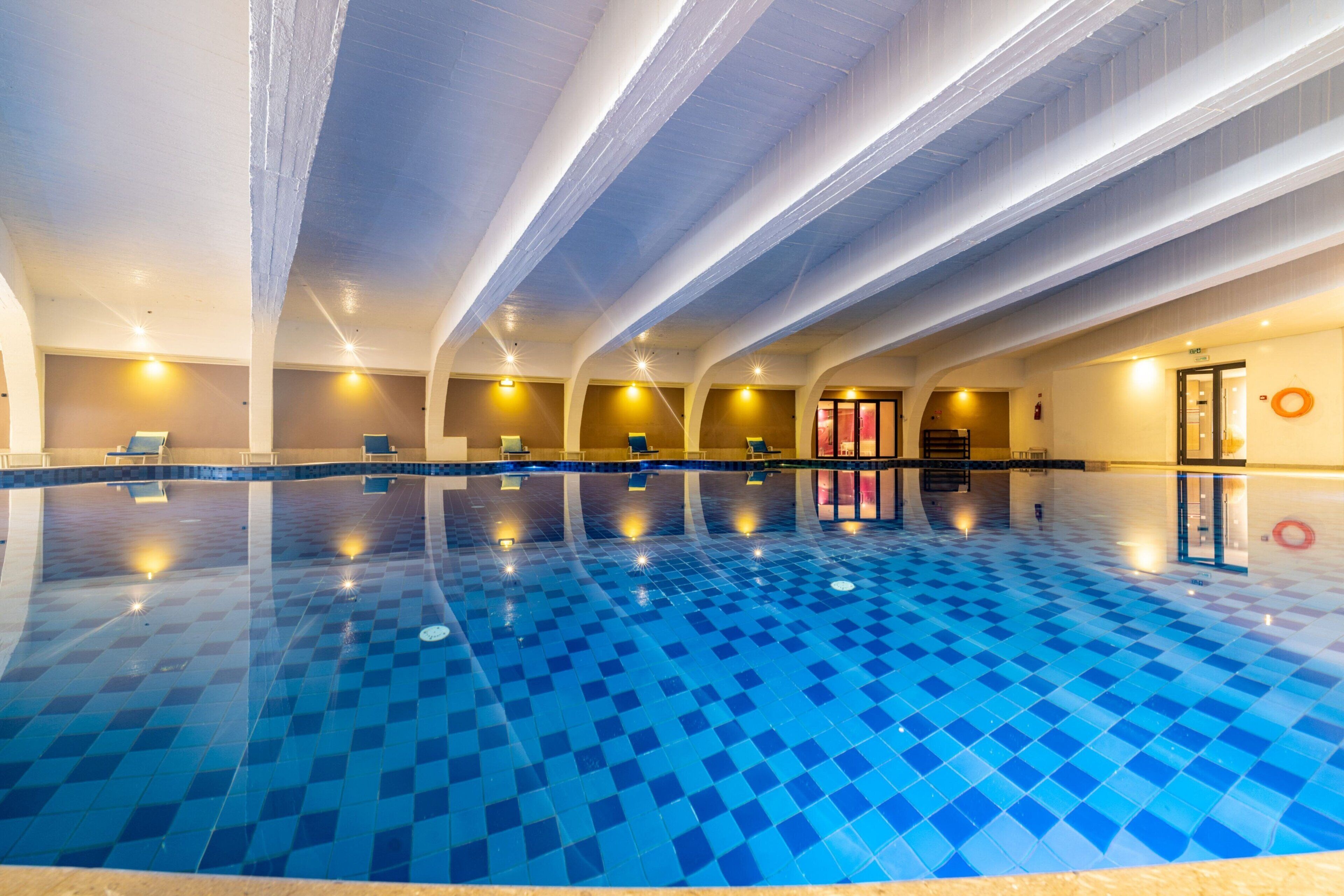 Una piscina interior amb terra de rajoles blaves a quadres, diverses lànies i il·luminació a la part superior.