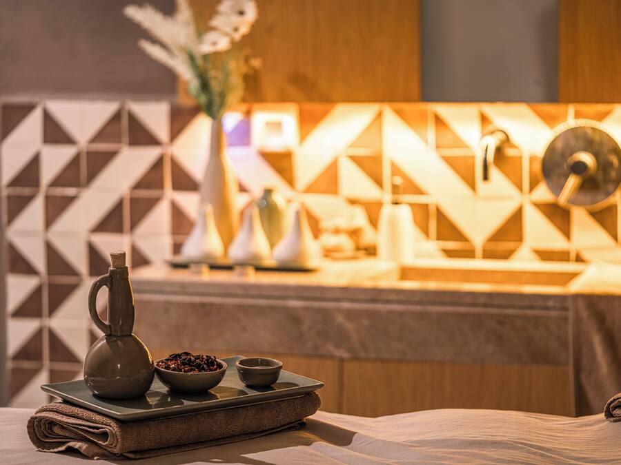 A neatly arranged spa area with a towel, a tray with a bowl of nuts, a small pitcher, and a decorative vase.