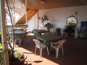 An outdoor patio area with a table and chairs, potted plants, and a mirror on the wall. - Hotel Andrea Doria (Viareggio)