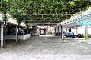 A covered parking area with a central pathway leading to a building entrance. - Hotel Andrea Doria (Viareggio)