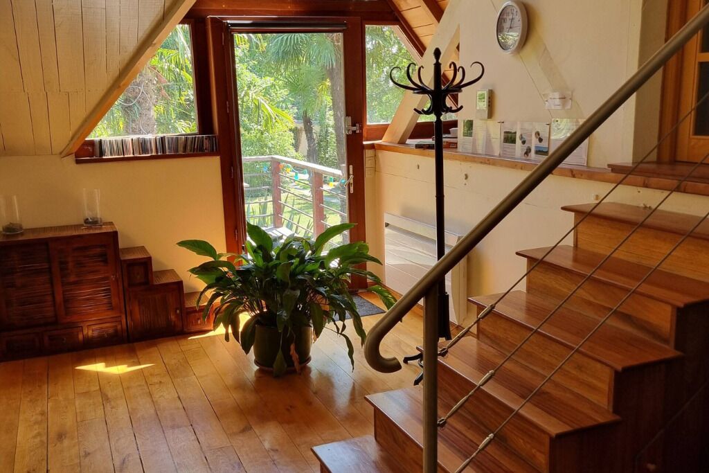 A wooden staircase with a metal handrail, a wooden bench, and a potted plant in a room with wooden floors and a sloped ceiling.