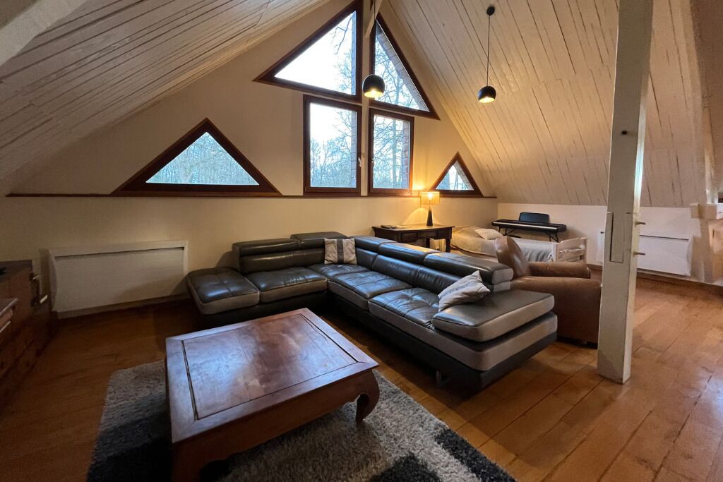 Ein Loft-Zimmer mit einer großen Eckcouch, einem Holztisch und einem Kamin.