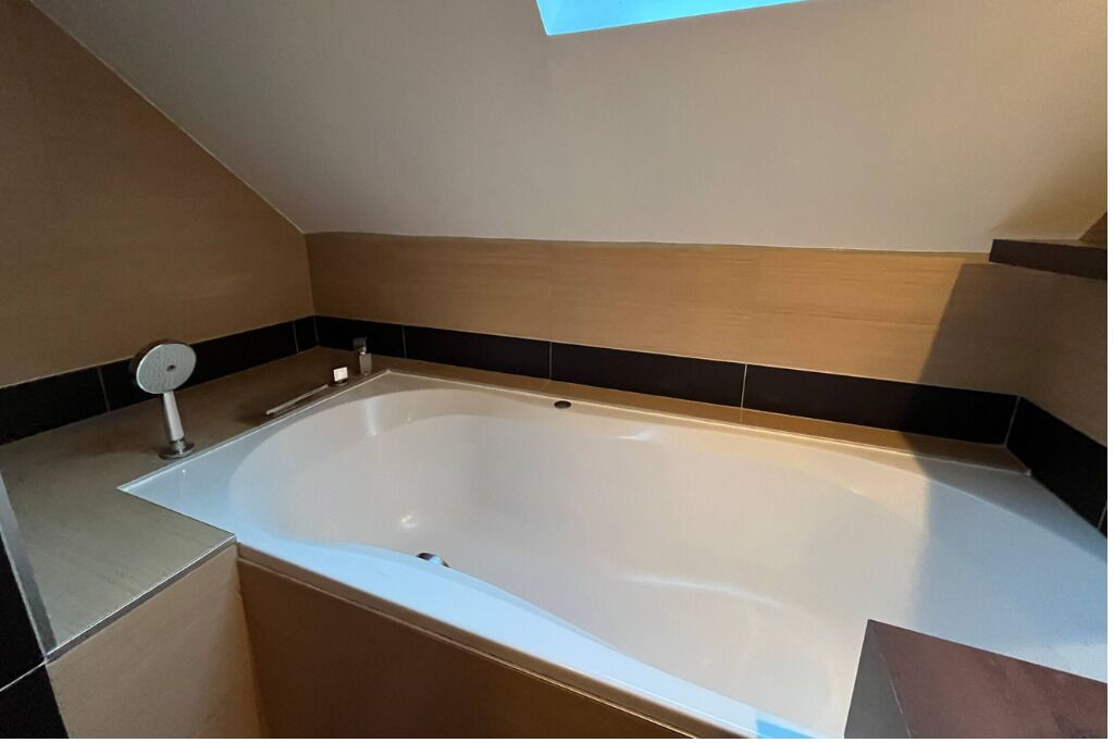 Un baño moderno con una bañera independiente, un perchero y un ventanal pequeño.