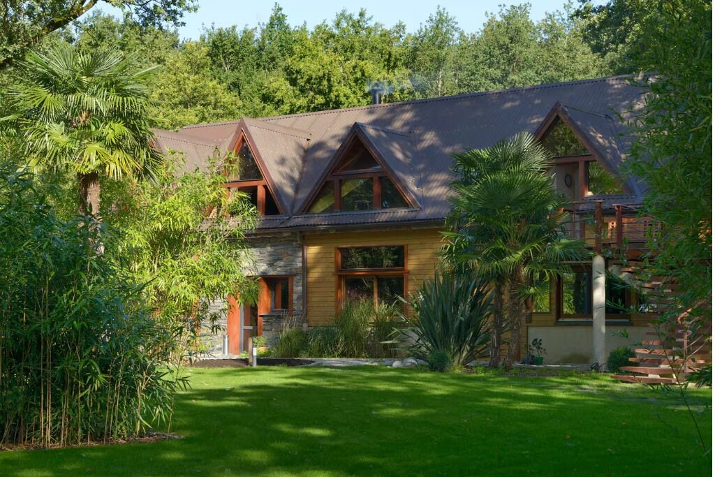 A two-story house with a stone facade, wooden trim, and a sloped roof.