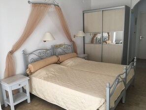 Un dormitorio con cama, mesitas de noche, un armario y un dosel.