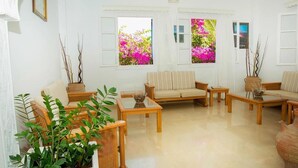 A living room with a sofa, two armchairs, a coffee table, and a large vase. - Avra Hotel (Santorini)