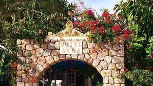 A stone archway leading to a hotel entrance with a sign above it. - Avra Hotel (Santorini)