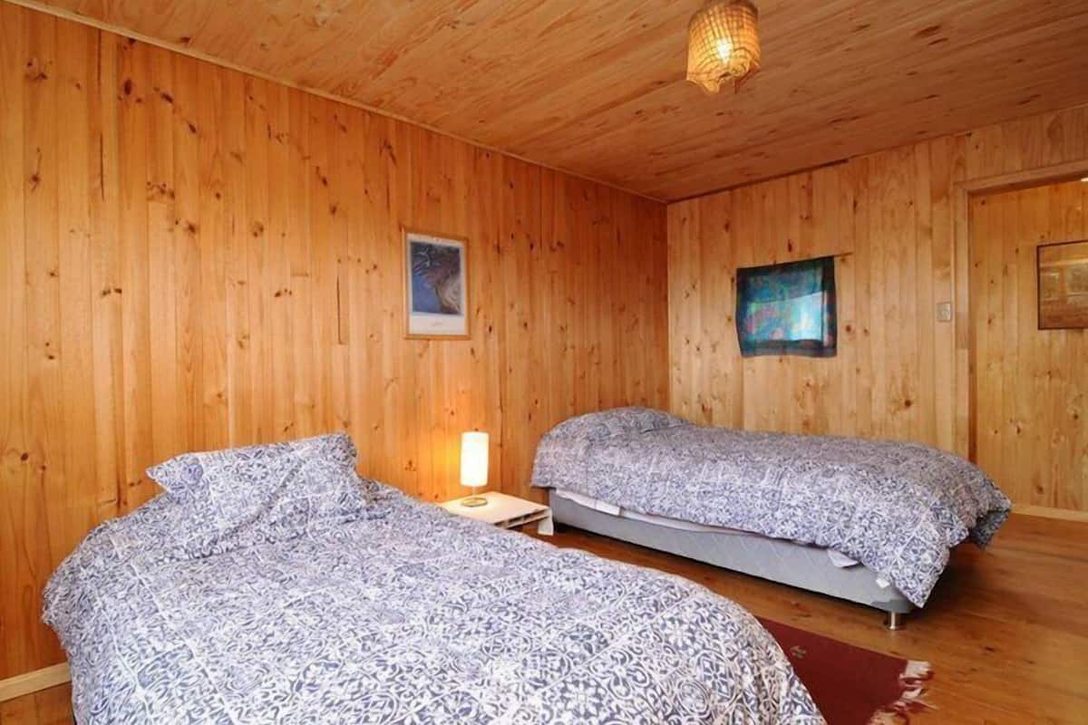 A wooden-paneled room with two beds, each with patterned bedding.
