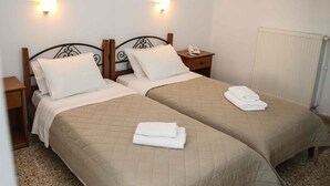 Une chambre double avec deux lits, chacun doté d’une tête de lit, de tables de chevet et de lampes fixées au mur.