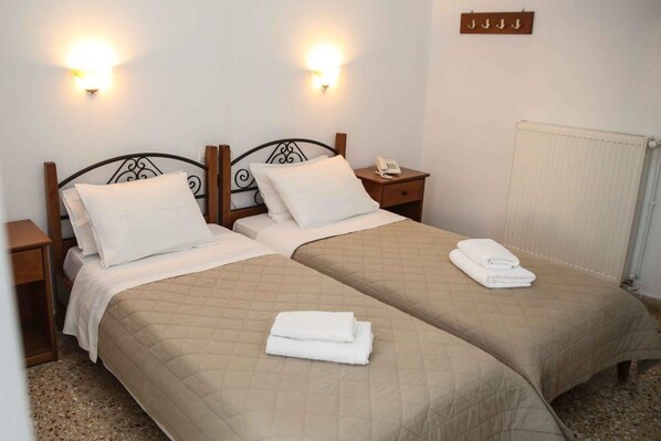 Habitación doble con dos camas, cada una con cabecera, mesitas de noche y lámparas de pared.