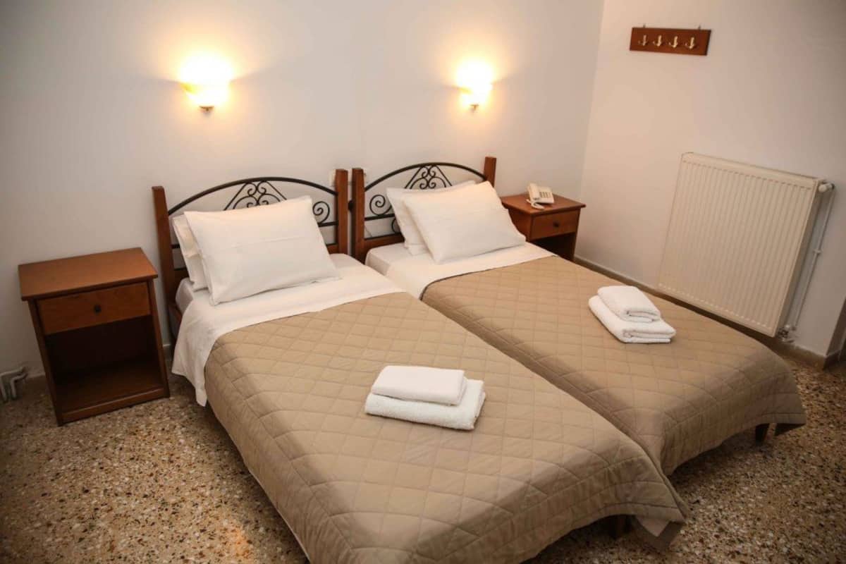 A double bed room with two bedside tables, a nightstand, and a wall-mounted light fixture.