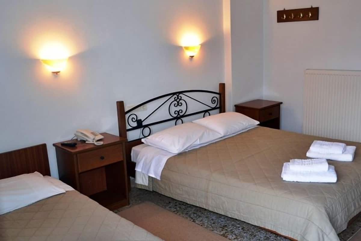 A hotel room with a double bed, two bedside tables, a telephone, and two wall-mounted light fixtures.